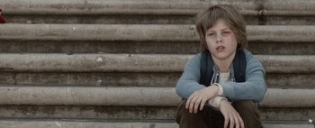 Movie still from “Hesher” (2010), directed by Spencer Susser – A young boy sitting on a set of stairs; Medium shot, Low angle