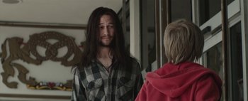 Movie still from “Hesher” (2010), directed by Spencer Susser – A man with long black hair and a long beard standing in front of a woman; Close Up shot, Over the shoulder angle