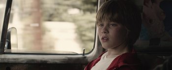 Movie still from “Hesher” (2010), directed by Spencer Susser – A boy sitting in a car looking out the window; Close Up shot, Over the shoulder angle