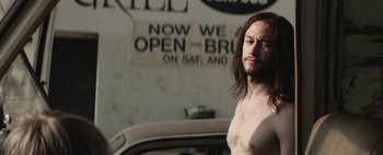 Movie still from “Hesher” (2010), directed by Spencer Susser – A man with long hair standing next to a car; Close Up shot, High angle