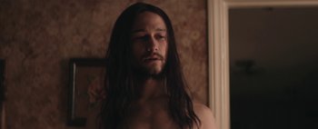 Movie still from “Hesher” (2010), directed by Spencer Susser – A man with long black hair and no shirt; Close Up shot, Over the shoulder angle