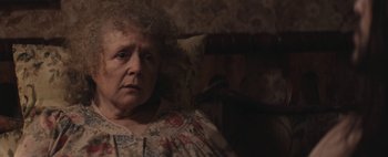 Movie still from “Hesher” (2010), directed by Spencer Susser – An older woman sitting in a chair looking at the camera; Close Up shot, Over the shoulder angle