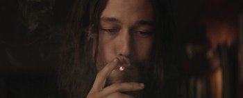 Movie still from “Hesher” (2010), directed by Spencer Susser – A man with long dark hair is smoking a cigarette; Close Up shot, Low angle