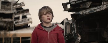 Movie still from “Hesher” (2010), directed by Spencer Susser – A young boy in a red jacket is standing in front of a camera; Close Up shot, Low angle