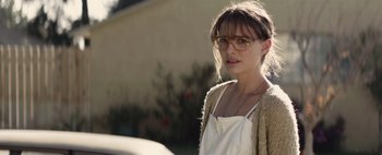 Movie still from “Hesher” (2010), directed by Spencer Susser – A woman wearing glasses standing next to a building; Close Up shot, Over the shoulder angle