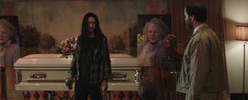 Movie still from “Hesher” (2010), directed by Spencer Susser – A man standing in front of an empty casket in front of a portrait; Medium shot, Over the shoulder angle