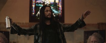 Movie still from “Hesher” (2010), directed by Spencer Susser – A man with long hair standing in front of a stained glass window; Medium shot, Low angle