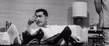 Movie still from “High and Low” (1963), directed by Akira Kurosawa – A black and white photo of a man sitting on a couch; Close Up shot, Low angle