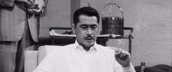Movie still from “High and Low” (1963), directed by Akira Kurosawa – Black and white photograph of a man in a white suit; Close Up shot, Low angle