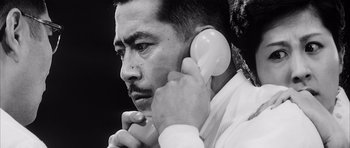 Movie still from “High and Low” (1963), directed by Akira Kurosawa – A black and white photo of a man holding a phone to his ear; Close Up shot, Low angle