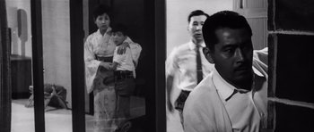 Movie still from “High and Low” (1963), directed by Akira Kurosawa – A black and white photo of a man and a woman and a boy; Medium shot, Low angle