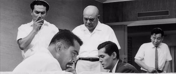 Movie still from “High and Low” (1963), directed by Akira Kurosawa – A group of men standing next to each other in a room; Medium shot, Low angle