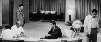 Movie still from “High and Low” (1963), directed by Akira Kurosawa – A black and white photo of a man in a suit sitting on a couch; Wide shot, High angle