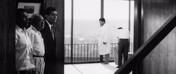 Movie still from “High and Low” (1963), directed by Akira Kurosawa – Three men are standing in front of a large window; Wide shot, Low angle