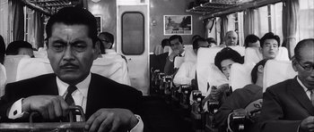 Movie still from “High and Low” (1963), directed by Akira Kurosawa – A black and white photo of people sitting on a train; Medium shot, Low angle