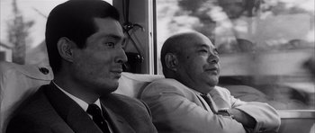 Movie still from “High and Low” (1963), directed by Akira Kurosawa – Two men sitting next to each other on a bus; Close Up shot, Low angle