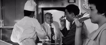 Movie still from “High and Low” (1963), directed by Akira Kurosawa – A group of men sitting around a table drinking wine; Medium shot, Over the shoulder angle