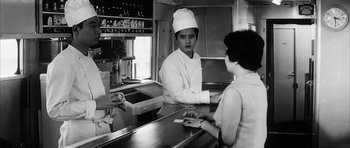Movie still from “High and Low” (1963), directed by Akira Kurosawa – An old black and white photo of a person in a kitchen; Medium shot, Low angle
