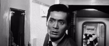 Movie still from “High and Low” (1963), directed by Akira Kurosawa – A black - and - white photo of a man in a suit and tie; Close Up shot, Low angle