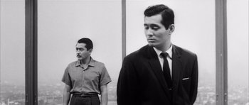 Movie still from “High and Low” (1963), directed by Akira Kurosawa – Two men standing next to each other in front of a wall; Medium shot, Low angle