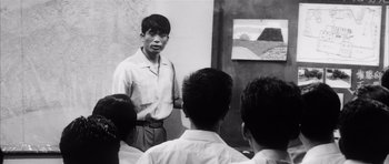Movie still from “High and Low” (1963), directed by Akira Kurosawa – Black and white photograph of a man in front of a group of people; Medium shot, Low angle