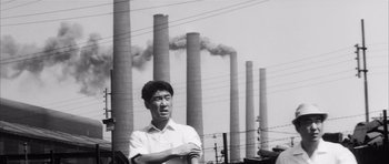 Movie still from “High and Low” (1963), directed by Akira Kurosawa – A man standing in front of a bunch of smokestacks; Medium shot, Low angle