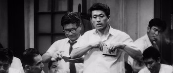 Movie still from “High and Low” (1963), directed by Akira Kurosawa – Two men in dress clothes and ties holding a camera; Medium shot, Low angle