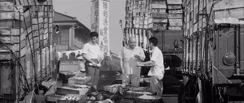 Movie still from “High and Low” (1963), directed by Akira Kurosawa – Three men standing in front of a pile of food; Wide shot, Low angle