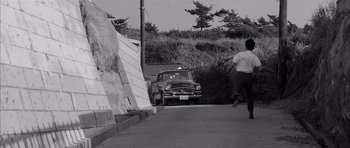 Movie still from “High and Low” (1963), directed by Akira Kurosawa – An old car parked on the side of the road; Extreme Wide shot, High angle