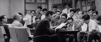Movie still from “High and Low” (1963), directed by Akira Kurosawa – A group of people sitting around a table; Medium shot, High angle