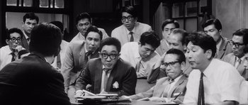Movie still from “High and Low” (1963), directed by Akira Kurosawa – A group of men sitting around a table; Medium shot, High angle