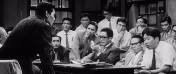 Movie still from “High and Low” (1963), directed by Akira Kurosawa – A group of men sitting around a table; Medium shot, High angle