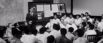 Movie still from “High and Low” (1963), directed by Akira Kurosawa – A group of men sitting in front of each other in a room; Wide shot, High angle