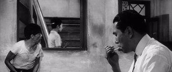Movie still from “High and Low” (1963), directed by Akira Kurosawa – A black and white photo of a man smoking a cigarette; Extreme Close Up shot, Over the shoulder angle