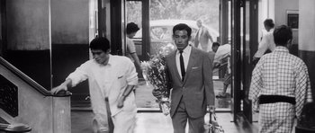 Movie still from “High and Low” (1963), directed by Akira Kurosawa – A black and white photo of a man walking down the street; Medium shot, Low angle