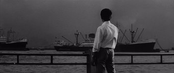 Movie still from “High and Low” (1963), directed by Akira Kurosawa – A black and white photo of a man looking out at a ship; Wide shot, Low angle