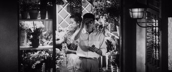 Movie still from “High and Low” (1963), directed by Akira Kurosawa – A black and white photo of a man saluting a woman; Medium shot, Low angle