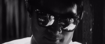 Movie still from “High and Low” (1963), directed by Akira Kurosawa – A black and white photo of a man wearing sunglasses; Extreme Close Up shot, Over the shoulder angle