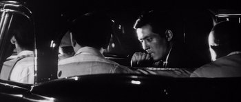 Movie still from “High and Low” (1963), directed by Akira Kurosawa – A man sitting in a car looking at another man; Close Up shot, Over the shoulder angle