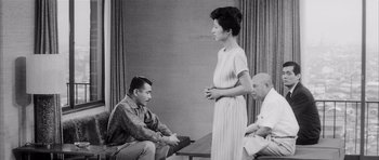 Movie still from “High and Low” (1963), directed by Akira Kurosawa – A man and a woman talking to a man sitting down; Medium shot, Over the shoulder angle