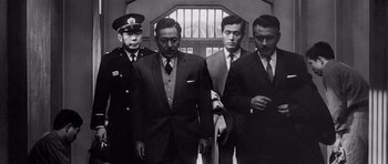 Movie still from “High and Low” (1963), directed by Akira Kurosawa – A group of men standing next to each other in suits; Medium shot, Low angle