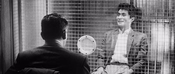 Movie still from “High and Low” (1963), directed by Akira Kurosawa – A man sitting in front of another man behind a fence; Medium shot, Over the shoulder angle