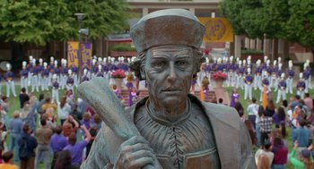 Movie still from “Higher Learning” (1995), directed by John Singleton – A statue of a man holding a baseball bat in front of a crowd of people; Extreme Wide shot, High angle