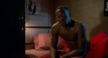Movie still from “Higher Learning” (1995), directed by John Singleton – A man sitting on top of a bed in a room; Medium shot, Over the shoulder angle