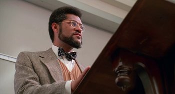 Movie still from “Higher Learning” (1995), directed by John Singleton – A man with a beard wearing glasses and a bow tie; Close Up shot, Low angle