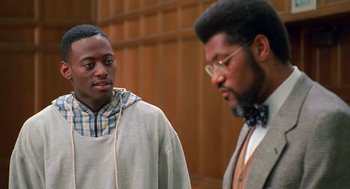 Movie still from “Higher Learning” (1995), directed by John Singleton – Two men are standing in a room and one of them is listening to headphones; Medium shot, Over the shoulder angle