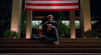 Movie still from “Higher Learning” (1995), directed by John Singleton – A person sitting on some steps holding a book; Wide shot, Low angle