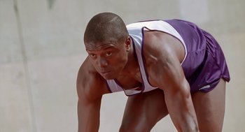 Movie still from “Higher Learning” (1995), directed by John Singleton – A man in a purple and white tank top crouching down; Close Up shot, Low angle