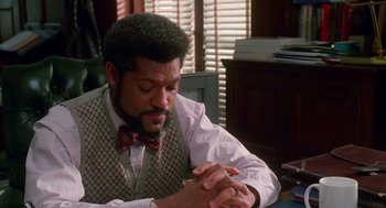 Movie still from “Higher Learning” (1995), directed by John Singleton – A man sitting at a table with his hands crossed; Close Up shot, High angle