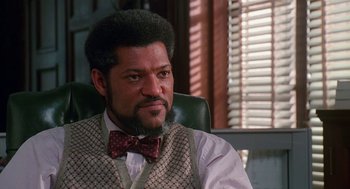 Movie still from “Higher Learning” (1995), directed by John Singleton – A man sitting in a chair wearing a bow tie; Close Up shot, Low angle